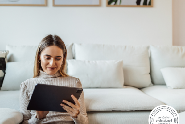 Junge Frau sitzt mit Tablet im Wohnzimmer